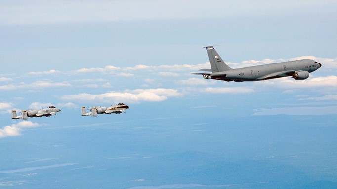 Image of KC-135 air refueling tanker flying with two A-10 fighter airplanes flying behind.